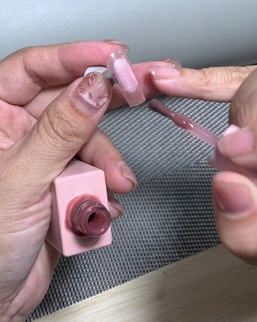 Un pinceau estompant les paillettes sur le bout de longle pour créer un effet dégradé.
