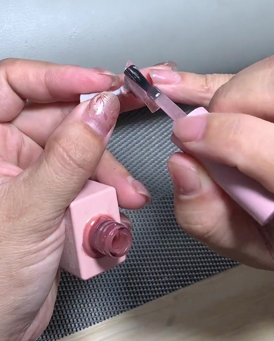 Un ongle avec un dégradé de paillettes placé dans une lampe UV pour catalyser.