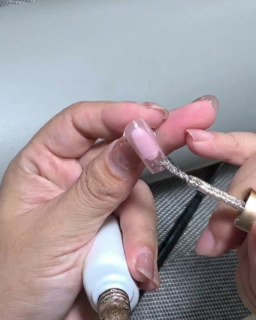 Un outil en silicone pressant la feuille dor appliquée sur le bout de longle pour laplatir.