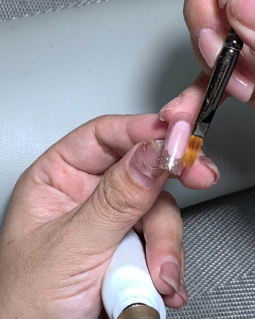 Une main placée dans une lampe UV pour catalyser lapplication de feuille dor.
