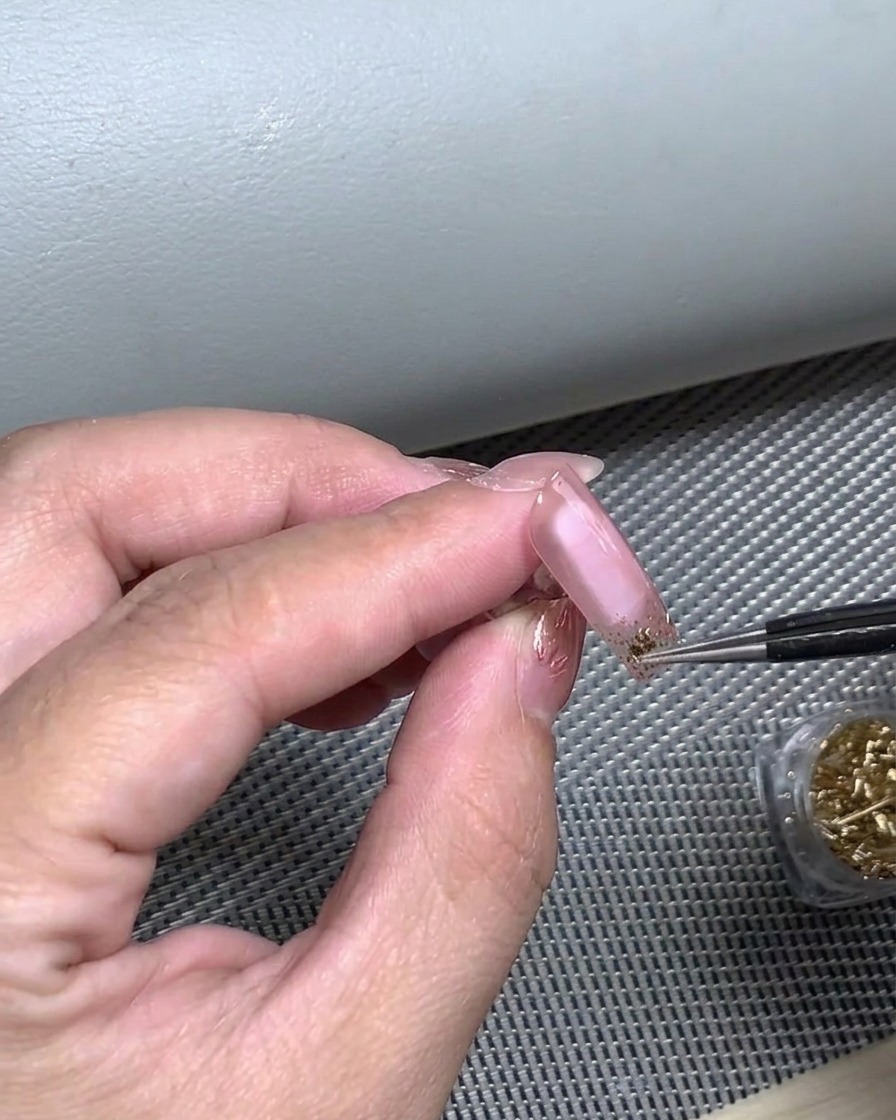 Un doigt appuyant sur un autocollant pour French pour assurer une adhérence totale à longle.