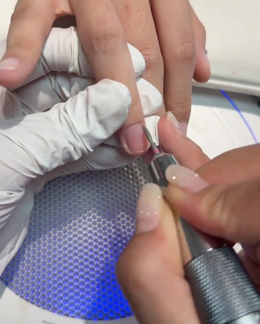 Gros plan sur une ponceuse à ongles utilisée pour nettoyer et ouvrir la zone des cuticules dun ongle.