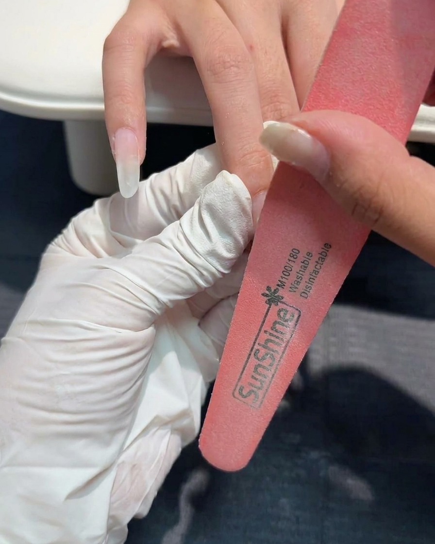 Une lime manuelle affinant la surface dun ongle en gel structuré.