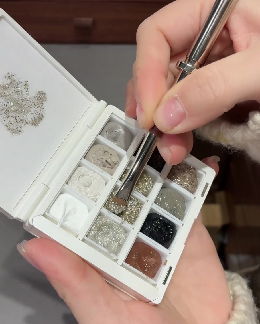 Vue en gros plan dun pinceau estompant des paillettes argentées sur un ongle pour créer un effet dégradé lisse.