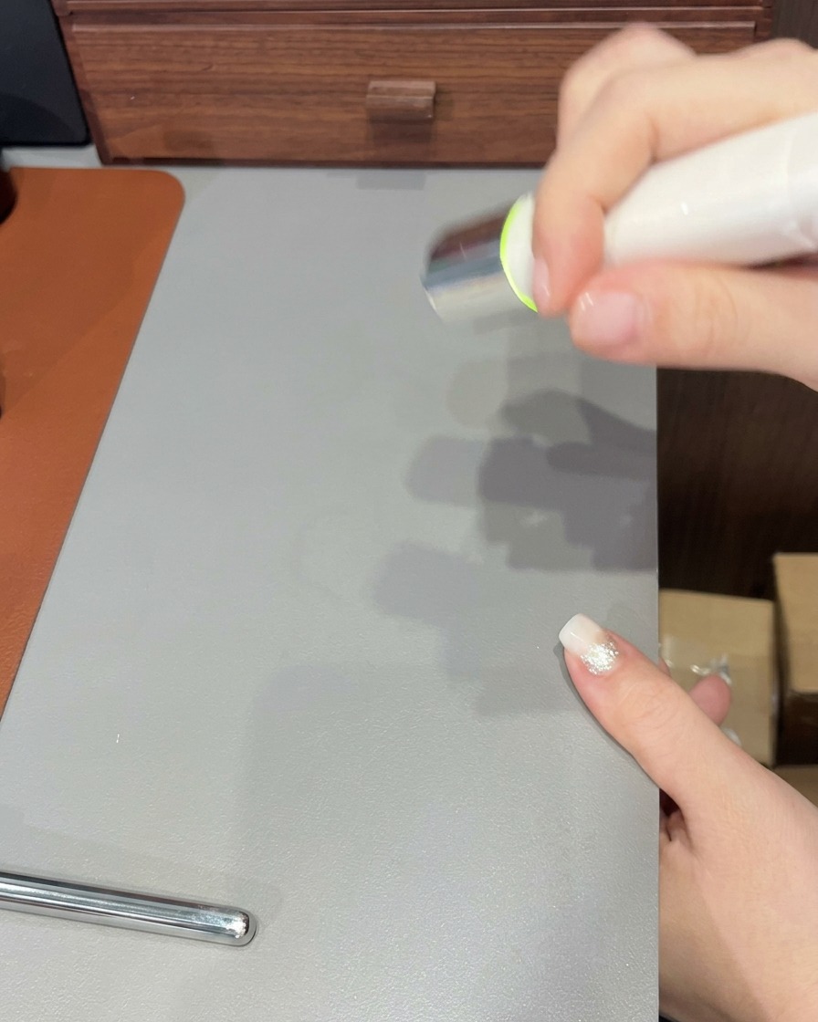 Un pinceau à ongles appliquant une dernière couche de gel transparent sur un ongle au dégradé terminé.