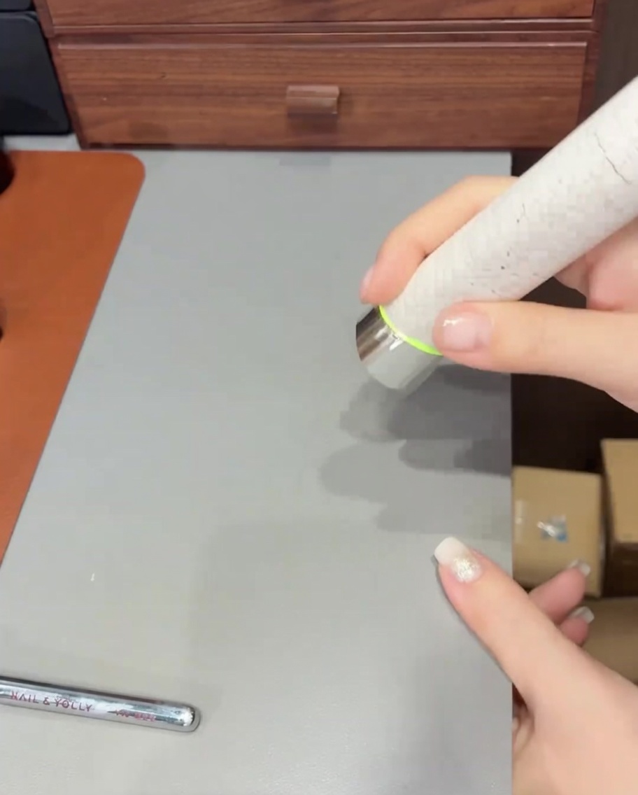 Un pinceau appliquant une couche finale de top coat transparent sur un ongle fini avec paillettes et ombré.