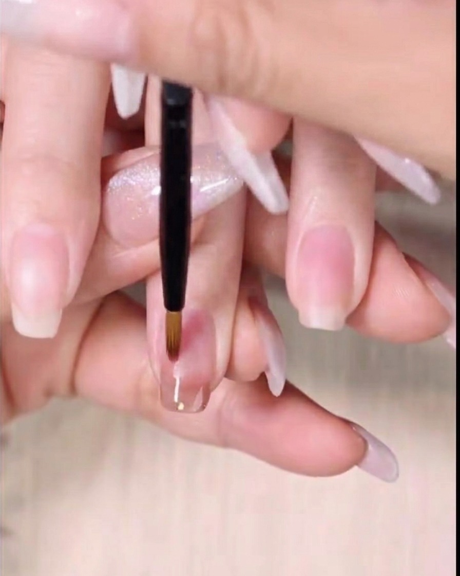 Un pinceau de détail fin balaie le bord inférieur du gel ambre humide vers le bas pour créer un dégradé.