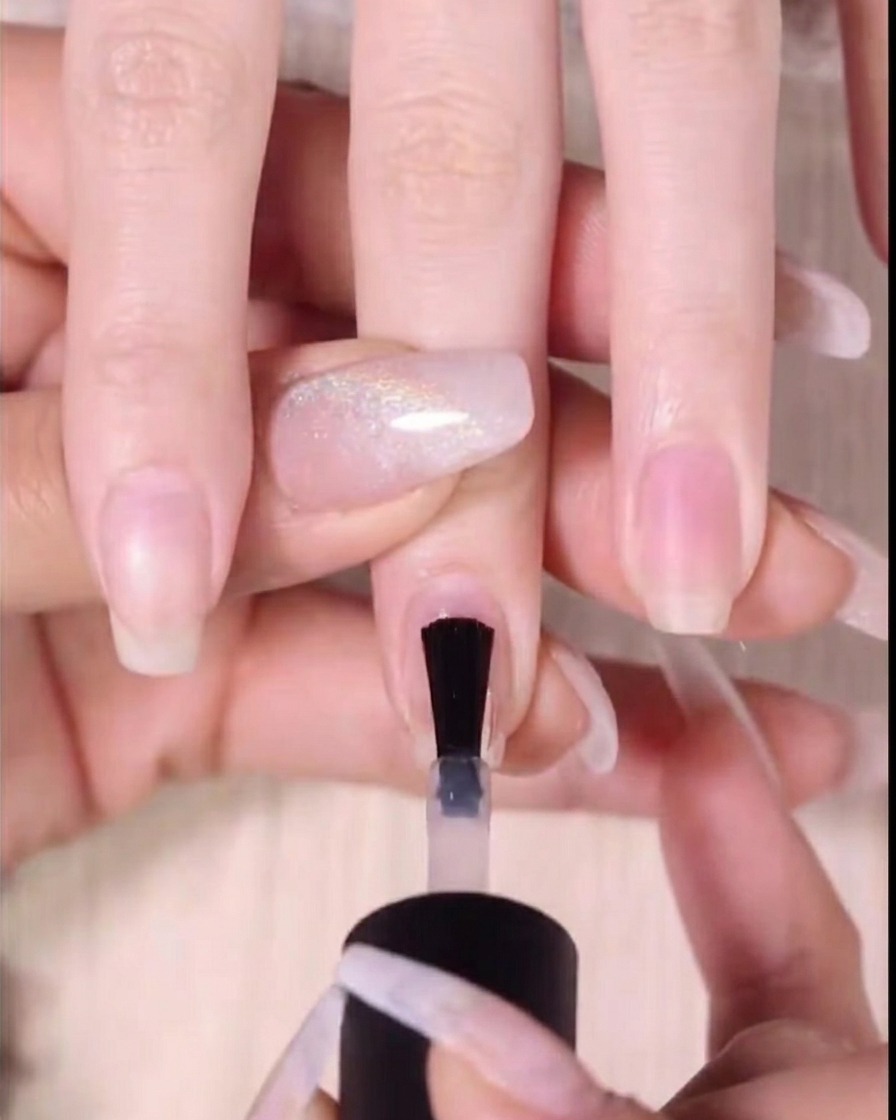 Gros plan dun pinceau appliquant du gel rouge sur les deux tiers supérieurs dun ongle.