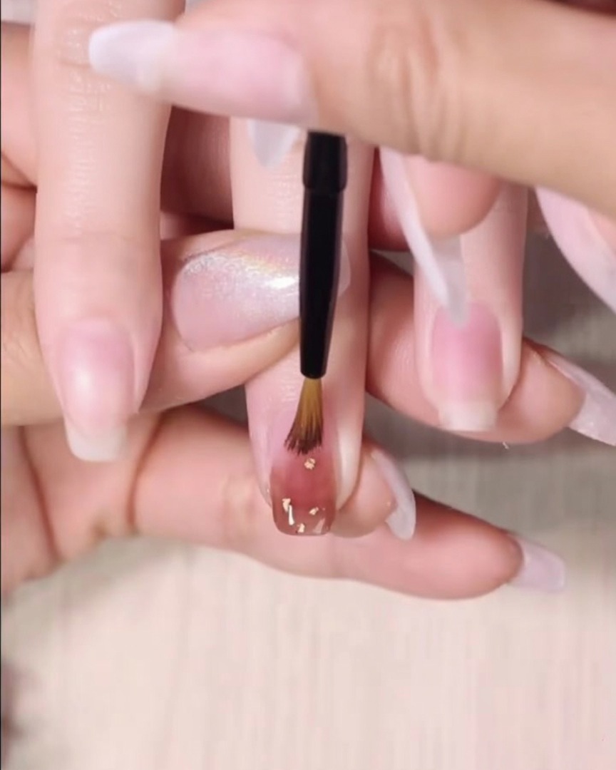 Un pinceau de détail fin estompe le bord inférieur dune deuxième couche humide de gel ambre.