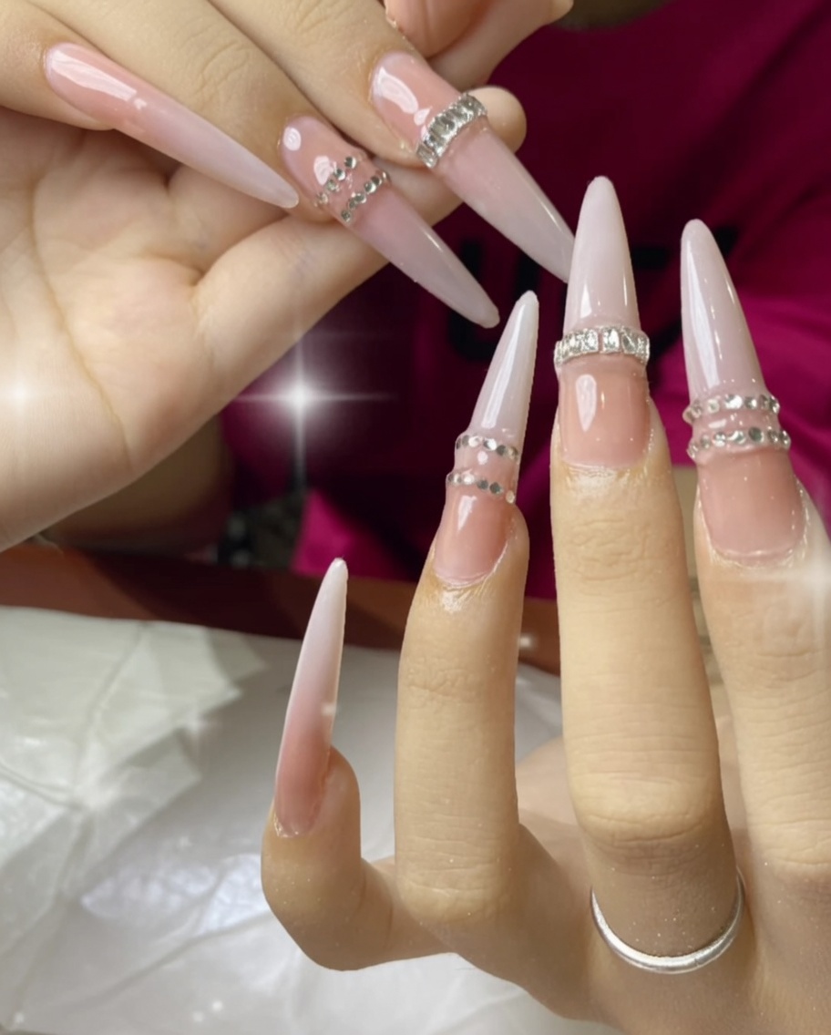 Une main sous une lampe UV, montrant la catalysation des ongles ornés de strass.
