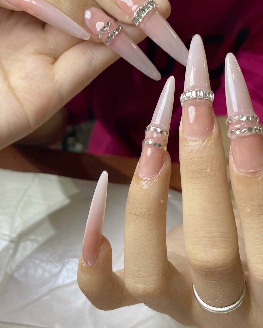 Gros plan dun ongle sur lequel une rangée de minuscules strass est appliquée et catalysée.