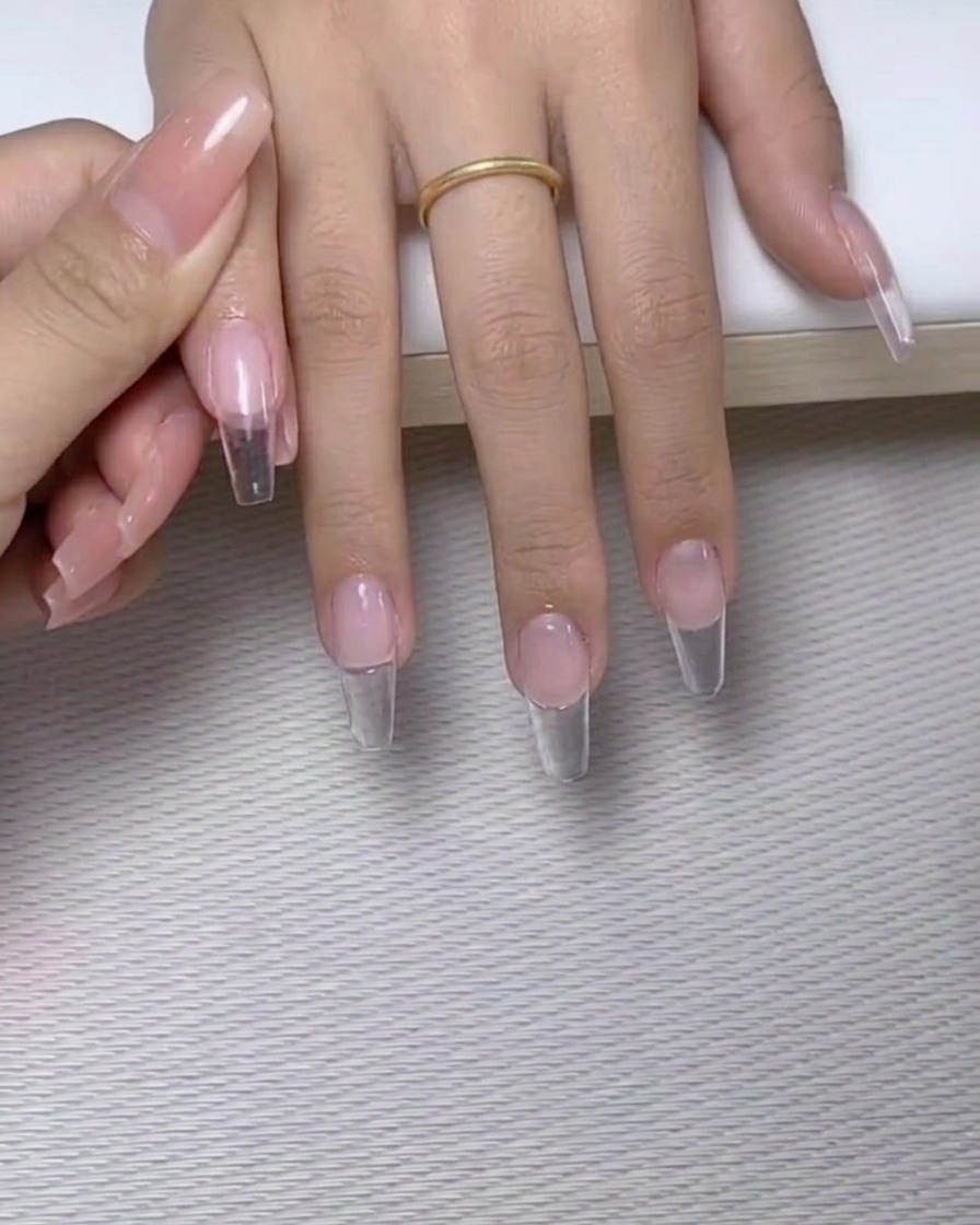 Un pinceau à pointe fine appliquant de petits points de colle à ongles transparente sur la surface dun ongle manucuré.