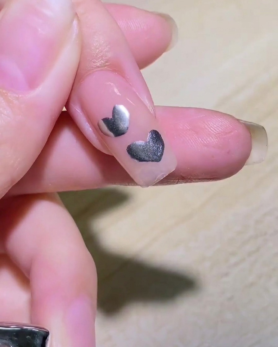 Gros plan montrant deux lignes argentées se croisant sur un ongle pour former une étoile.