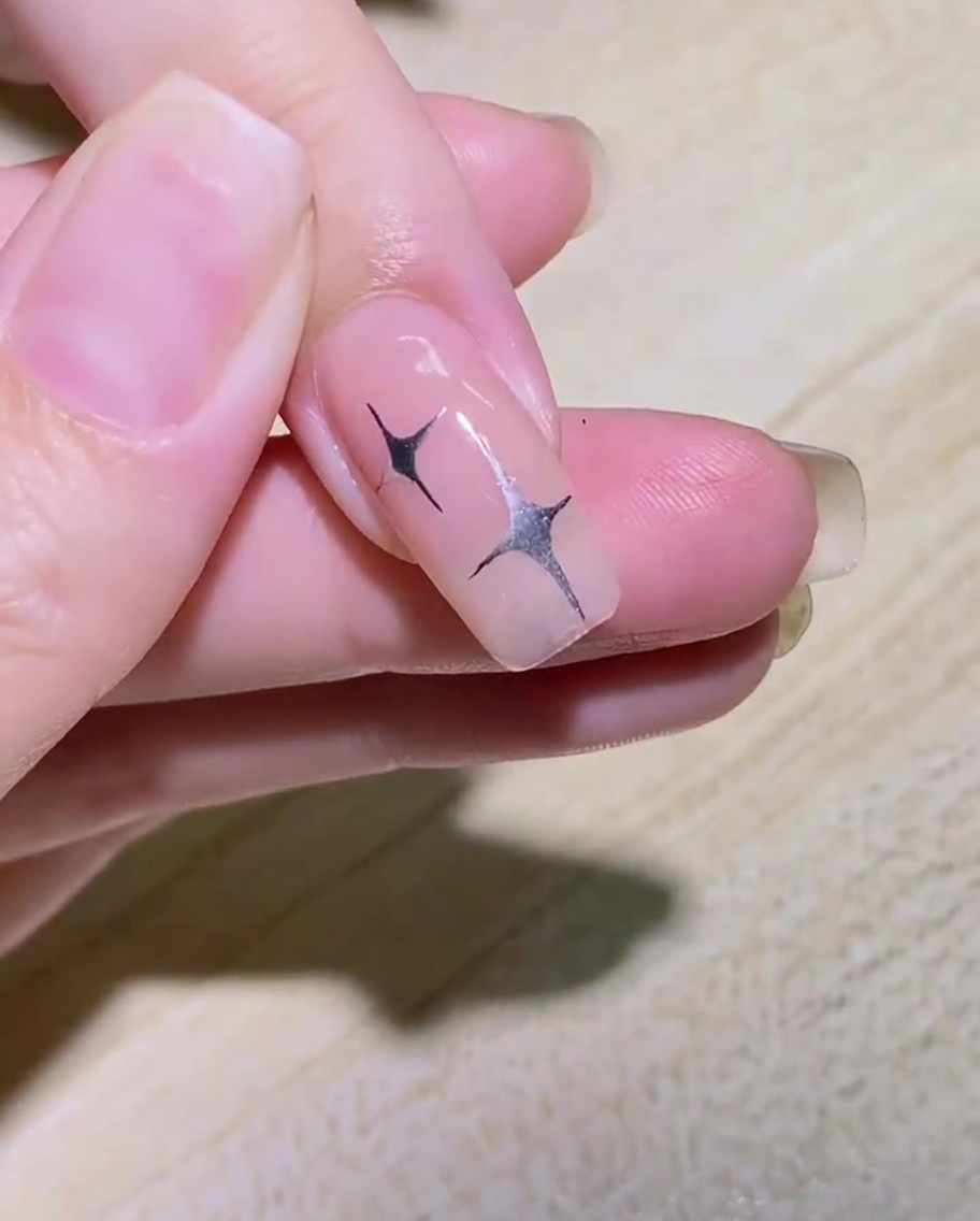 Un pinceau liner dessinant le contour courbe dune aile de papillon sur le côté dun ongle.