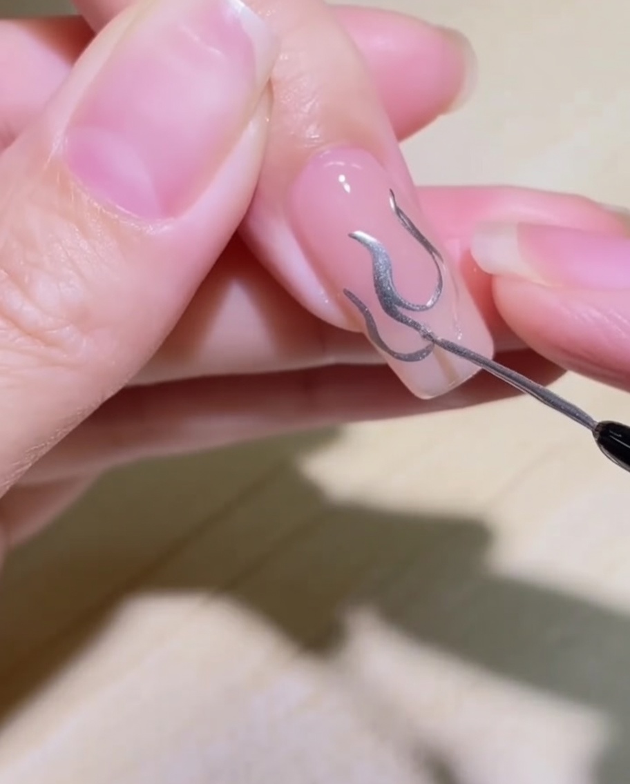 Gros plan du design de flamme en cours de remplissage avec le gel métallique argenté.