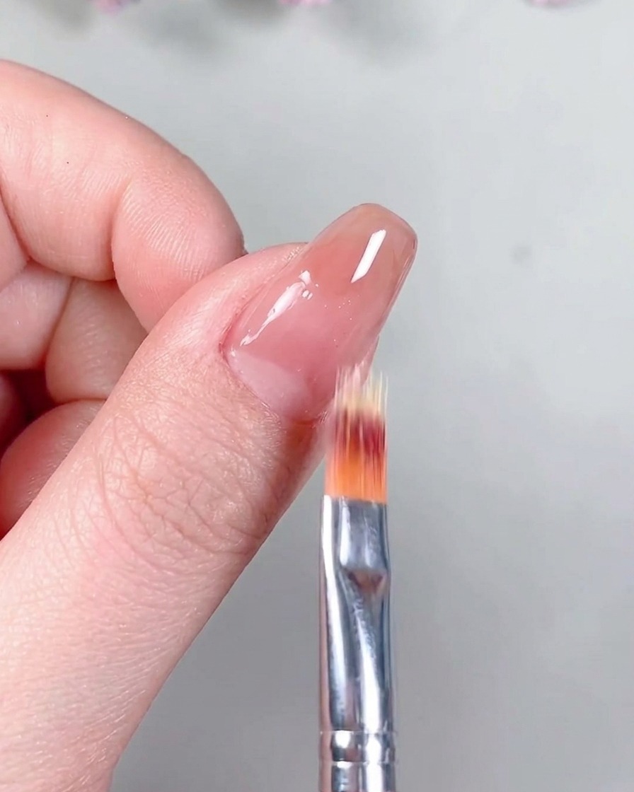 Un pinceau appliquant un vernis de finition mat transparent sur la base nude catalysée.