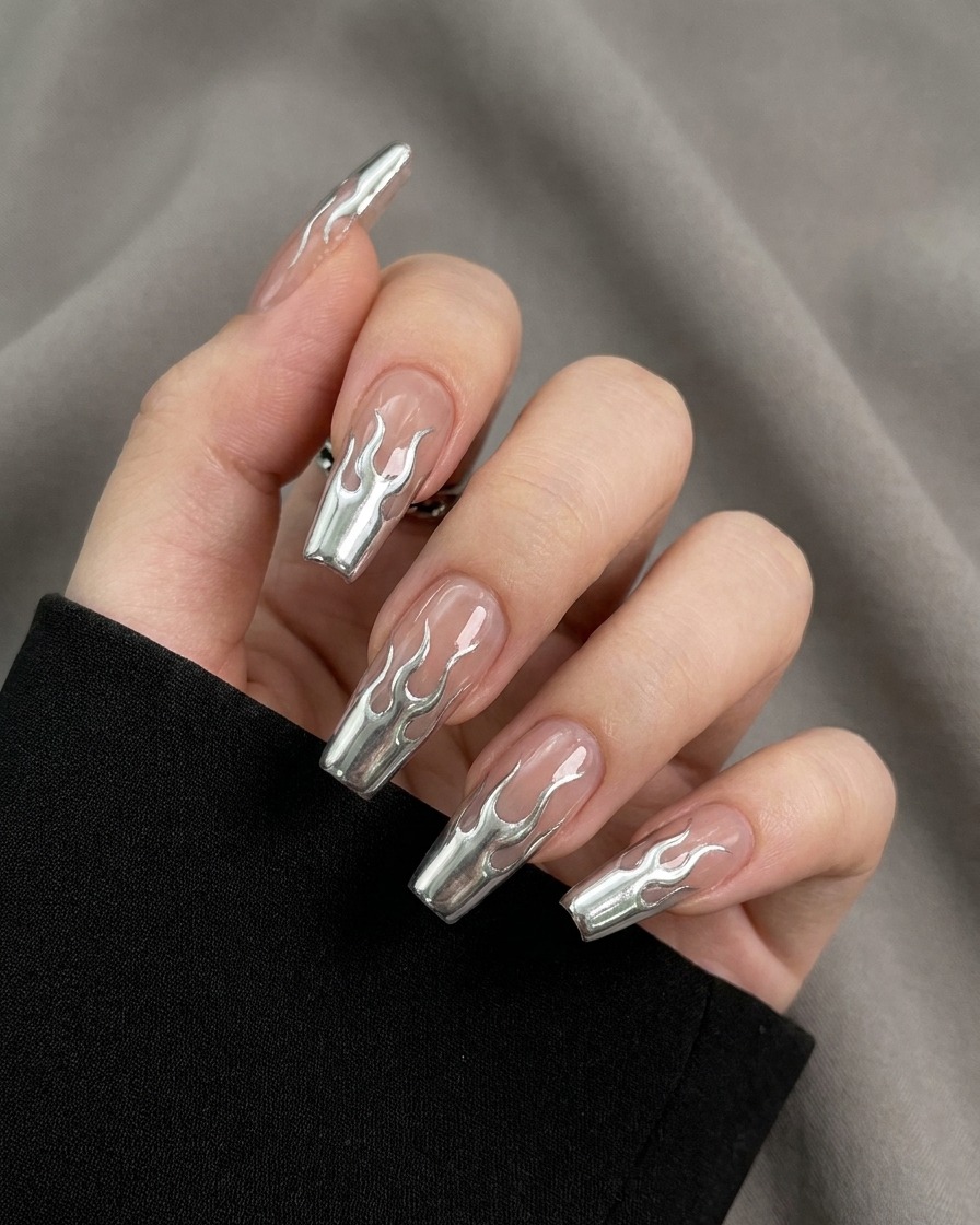 Gros plan dun pinceau remplissant les contours des flammes sur un ongle avec un gel argenté métallique hautement réfléchissant.