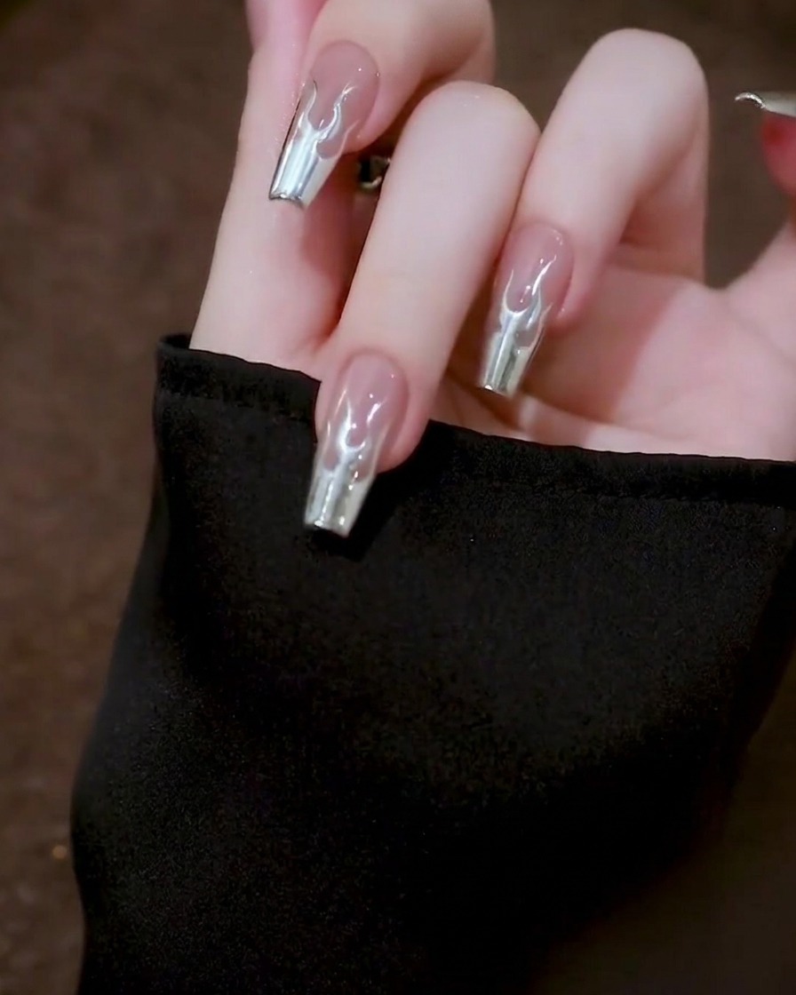 Vue de dessus dune main tenant un ongle immobile pendant que le gel métallique se stabilise pour une finition lisse.