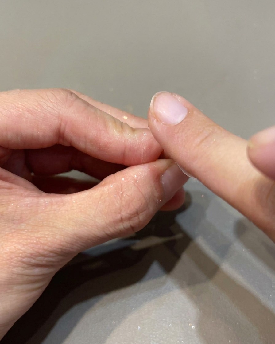 Un applicateur mousse frottant une poudre miroir irisée sur un ongle pour créer une finition brillante.