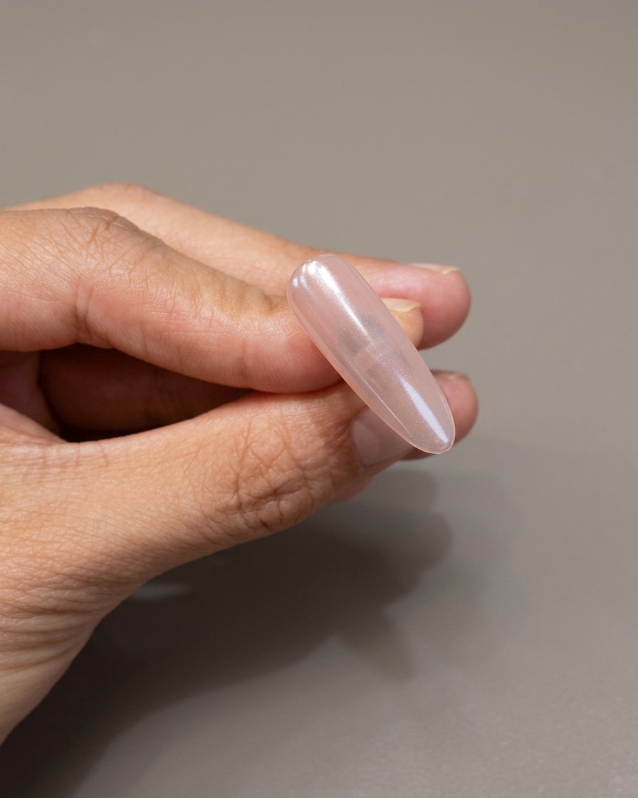 Un pinceau appliquant une couche protectrice de gel transparent sur un ongle chromé.