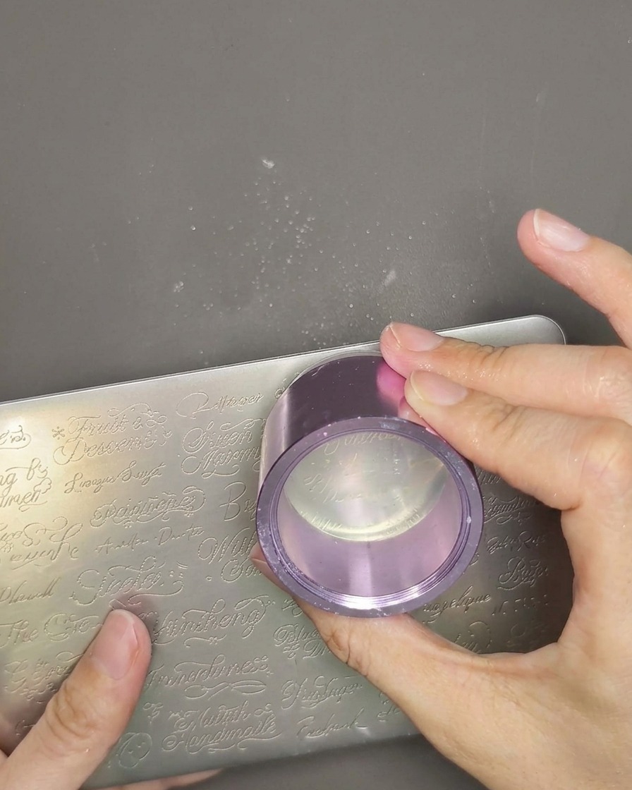 Vue rapprochée dun tampon en gel tenant un motif de texte avec une fine couche de vernis blanc.