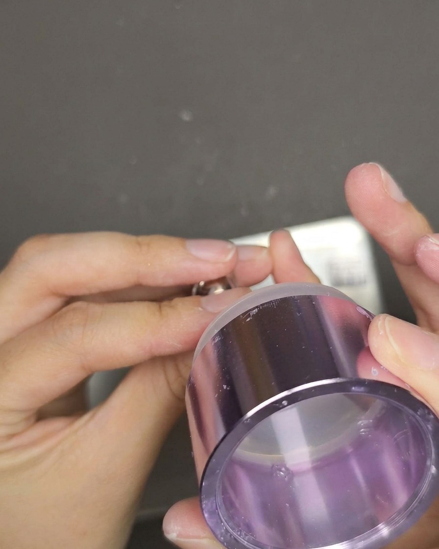 Un tampon en gel pressé sur un ongle rouge œil de chat pour transférer le texte blanc.