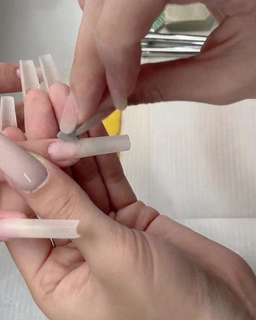 Un applicateur mousse tapotant le gel nude sur longle.