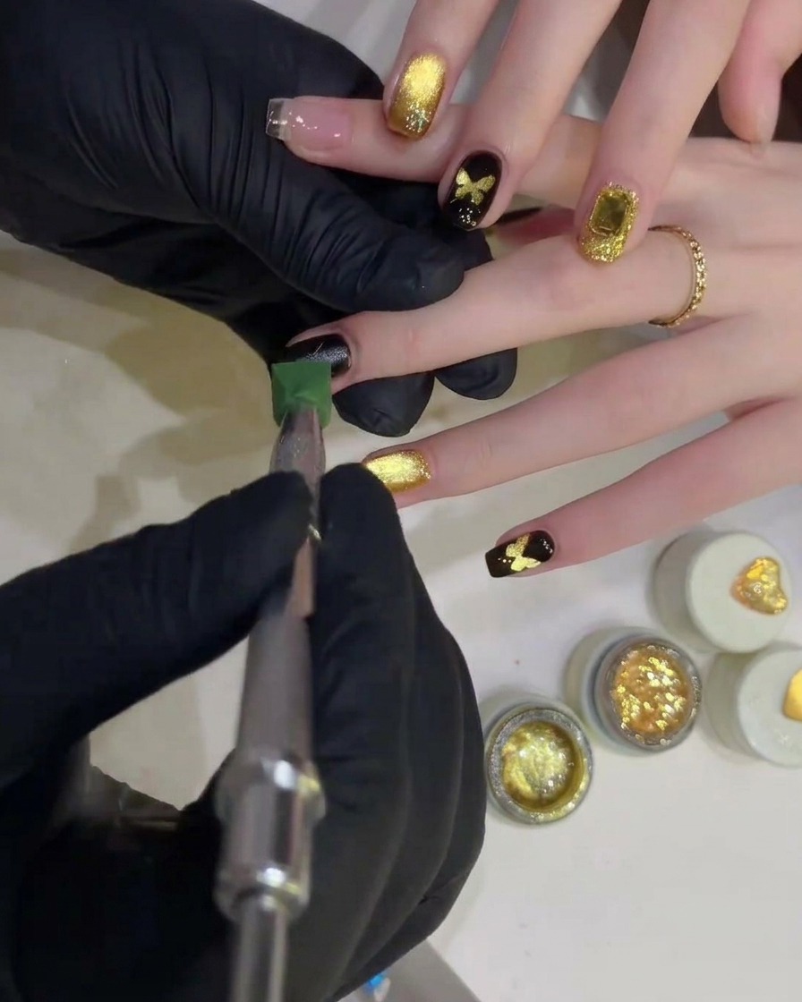 Gros plan sur une petite éponge de précision chargée de vernis gel noir opaque provenant dun petit pot.
