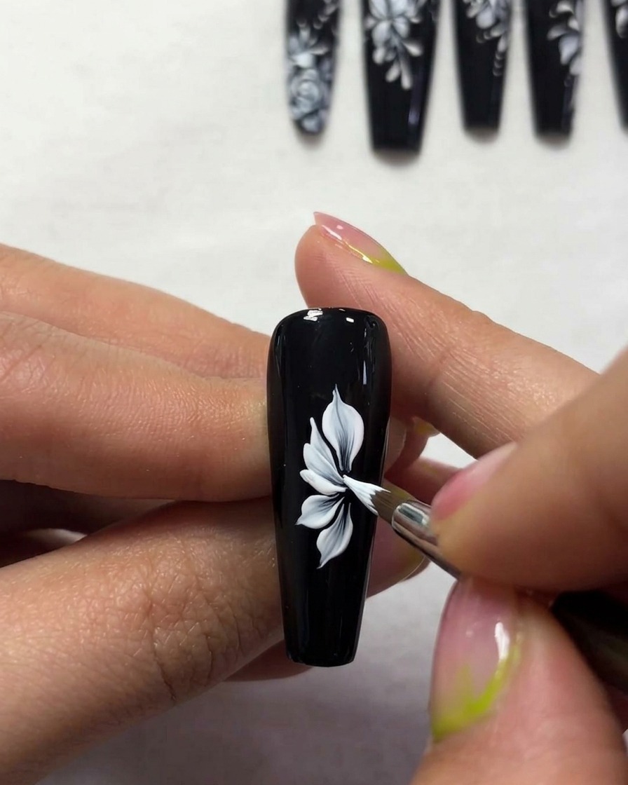 Gros plan dun pinceau créant des contours dailes de papillon blancs fins et élégants sur une surface dongle noire.