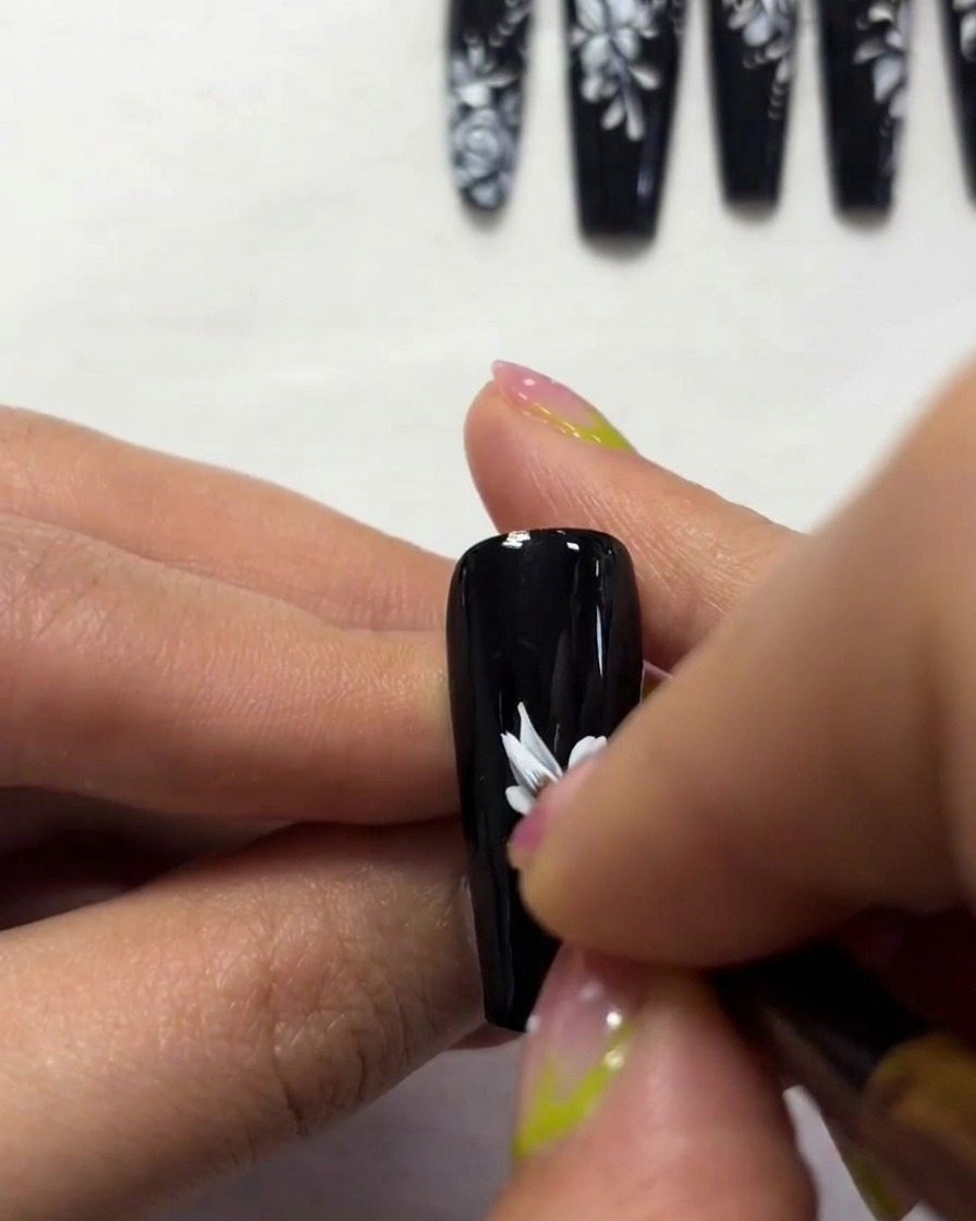 Vue rapprochée montrant les détails des bords des ailes du papillon avec de la peinture blanche sur un ongle noir.