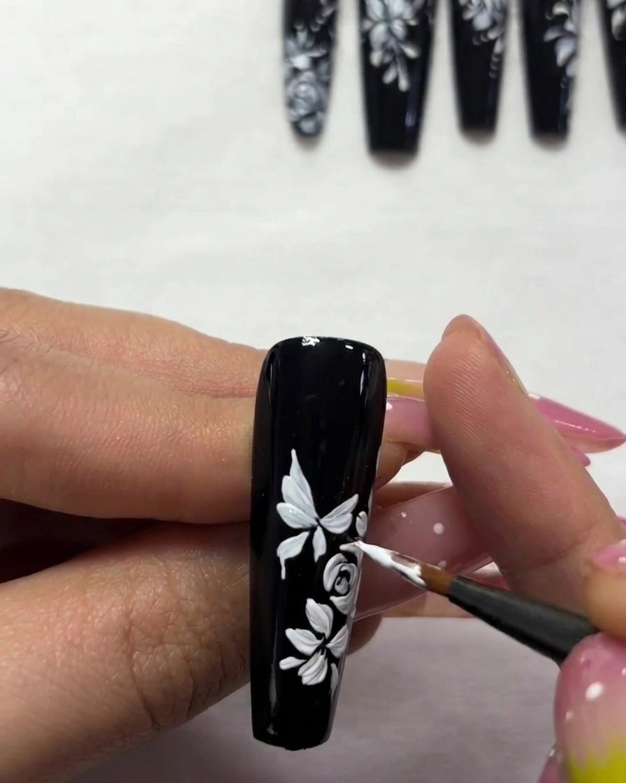 Gros plan détaillé montrant lajout dantennes blanches fines et de petits points entourant le nail art papillon.