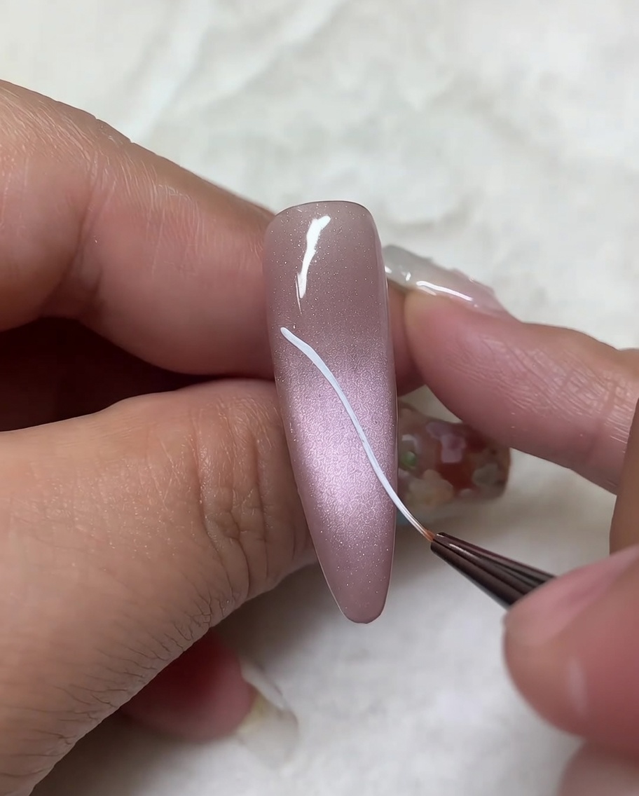 Un pinceau liner ajoutant des lignes courbes aux contours diagonaux précédents pour compléter la forme des ailes.
