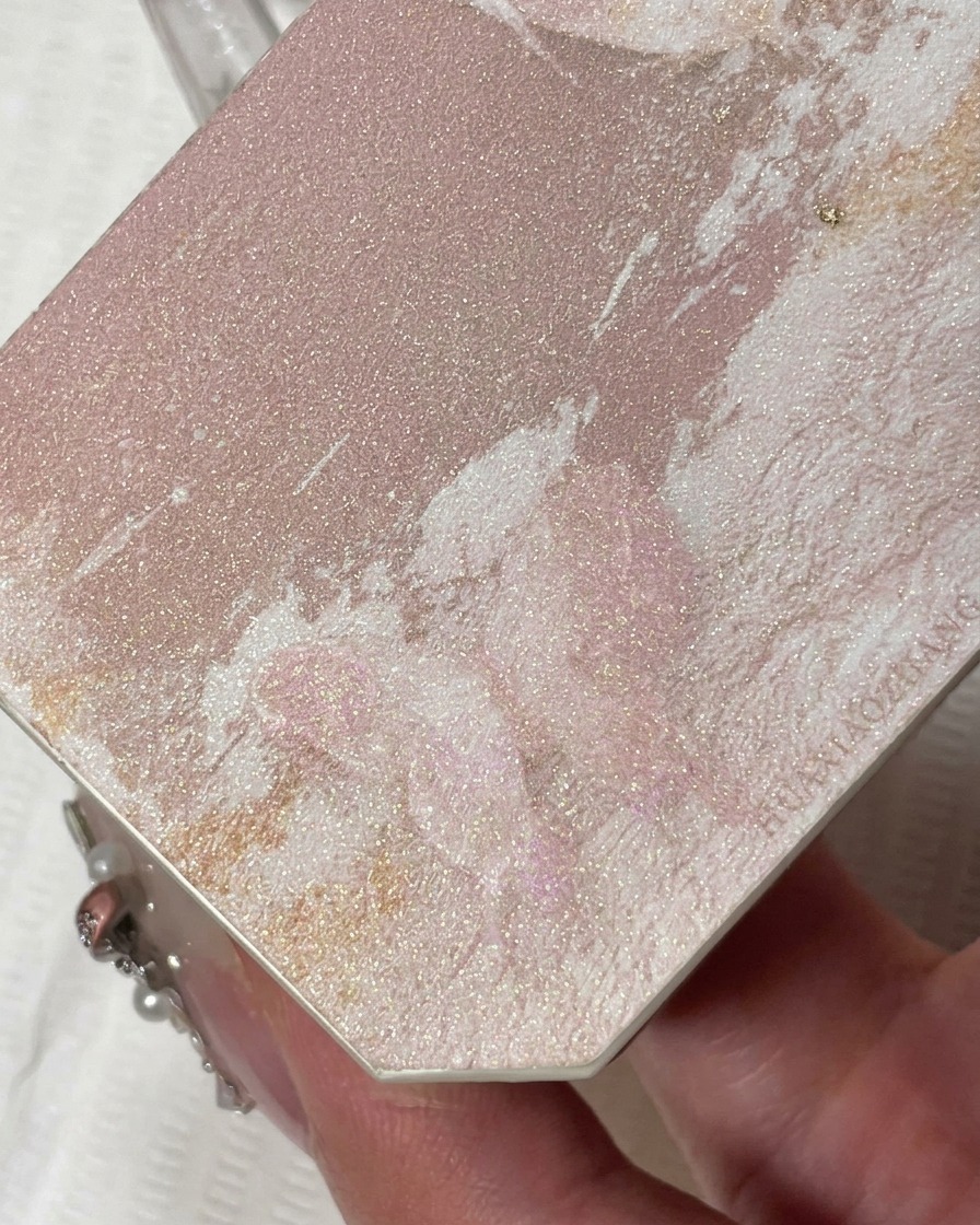 Gros plan dun pinceau liner fin appliquant un gel pailleté couleur champagne étincelant sur le bord libre.
