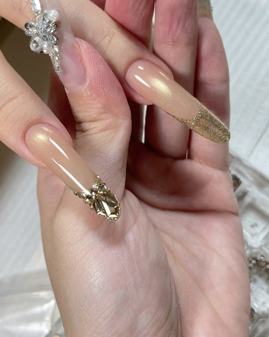 Un outil applicateur de précision déposant une petite perle de gel adhésif transparent sur longle à la base de la zone pailletée.