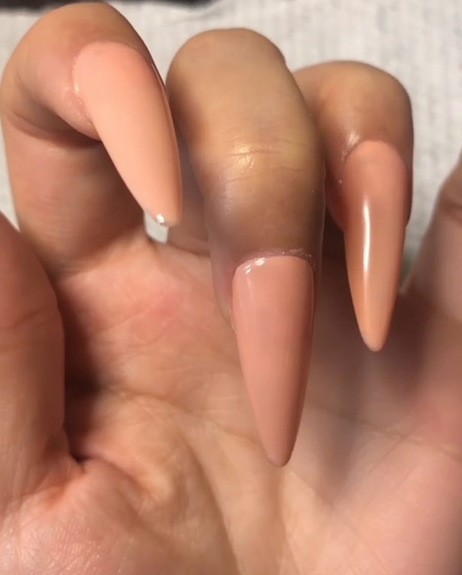 Un pinceau à ongles appliquant une fine couche de top coat sur le gel nude de lindex.