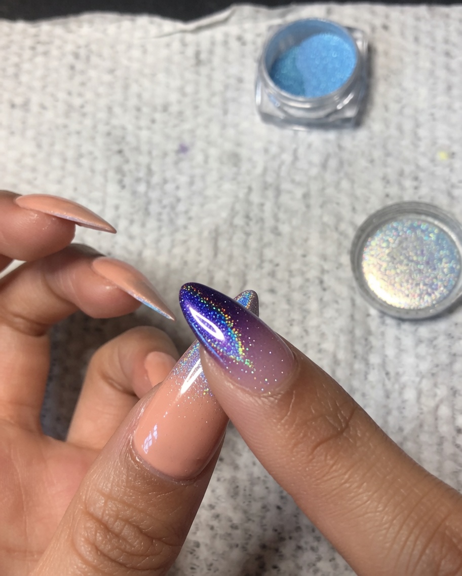 Gros plan dun doigt estompant délicatement la poudre chrome holographique sur le milieu dun ongle de pouce pour créer un fondu ombré doux.