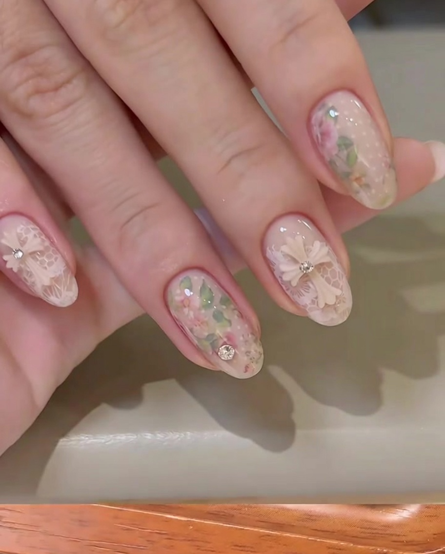 Un tampon transparent transférant un délicat motif de dentelle blanche sur un ongle nude.