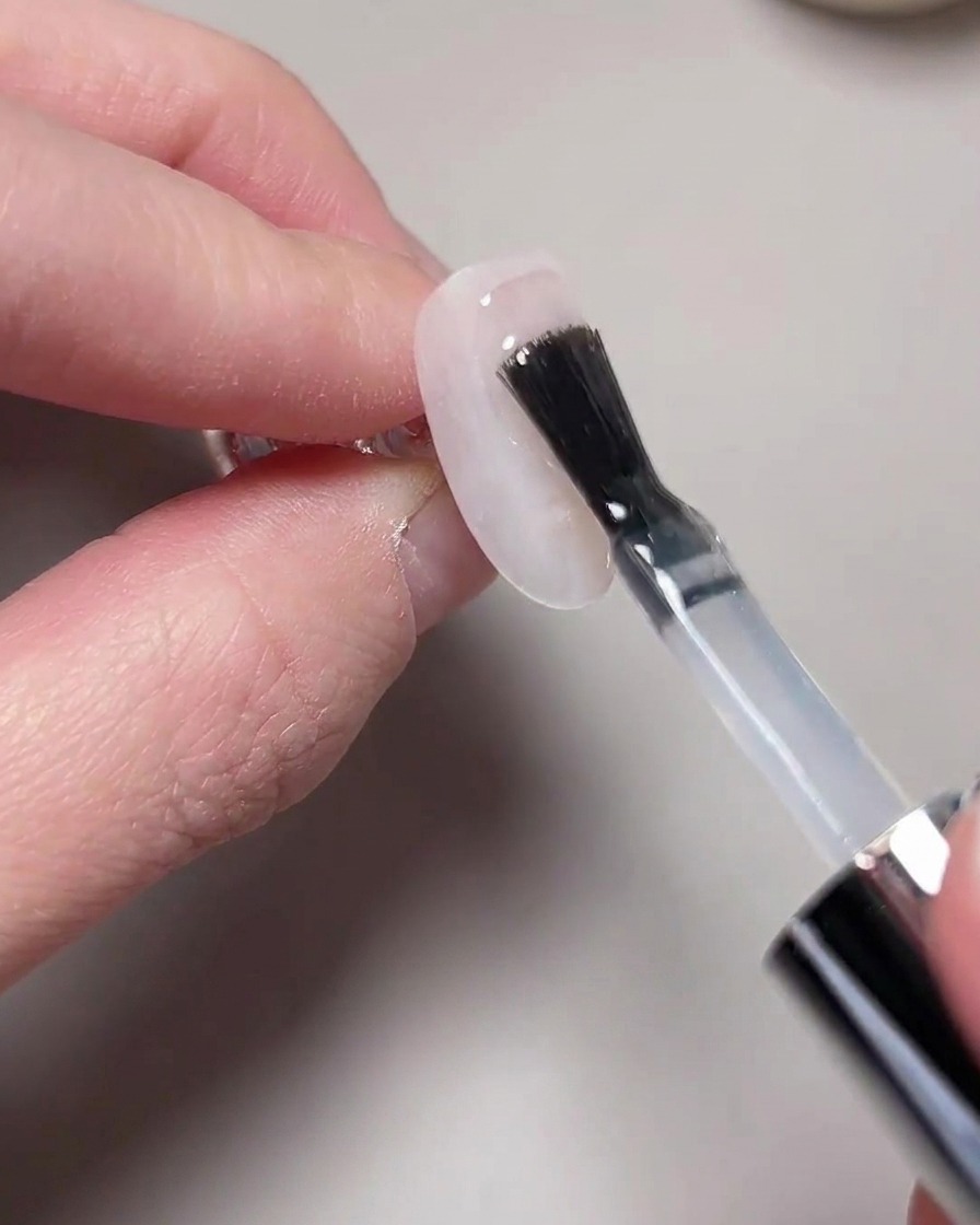 Une main positionnée sous une lampe UV/LED pour ongles pour la catalysation.