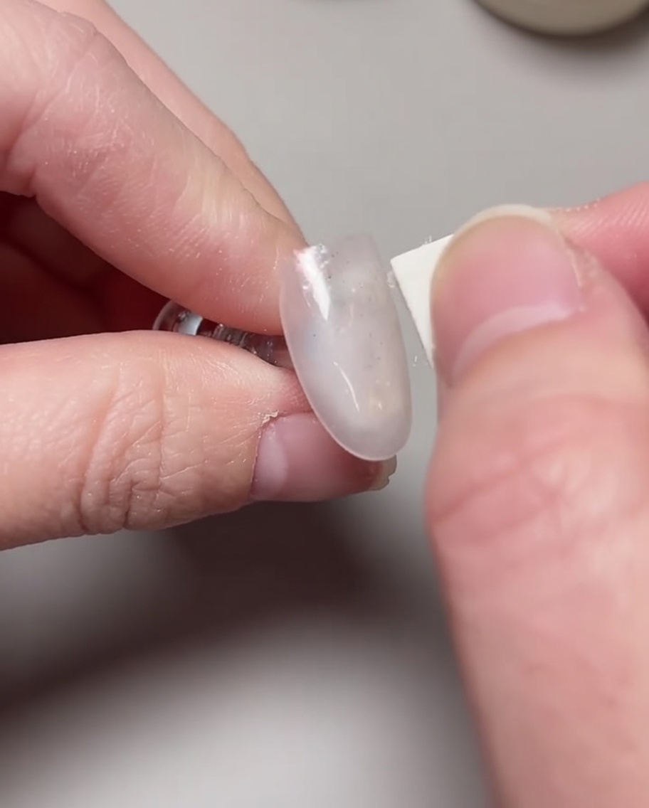 Un pinceau appliquant une deuxième couche de vernis gel litchi rose pour renforcer lopacité.