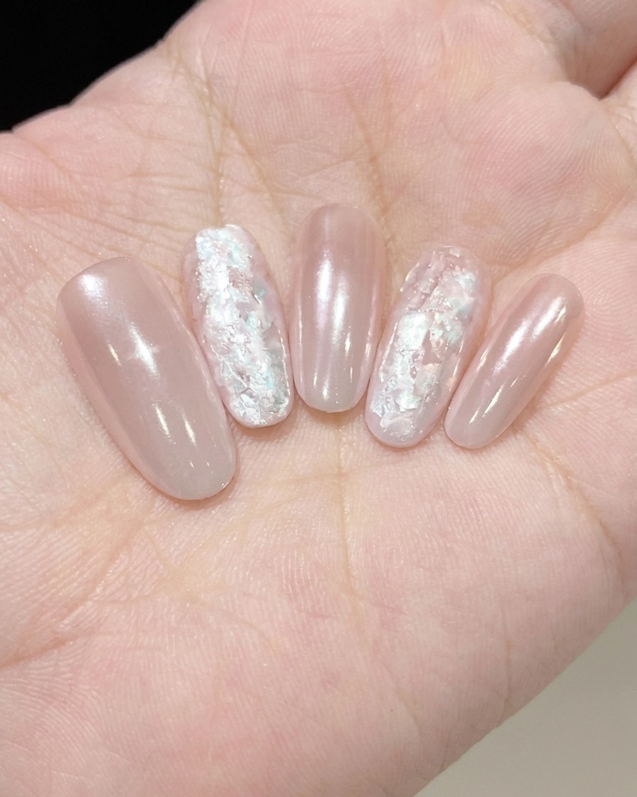 Un pinceau appliquant une fine couche de Fine Pearl Glue chatoyante sur un ongle.