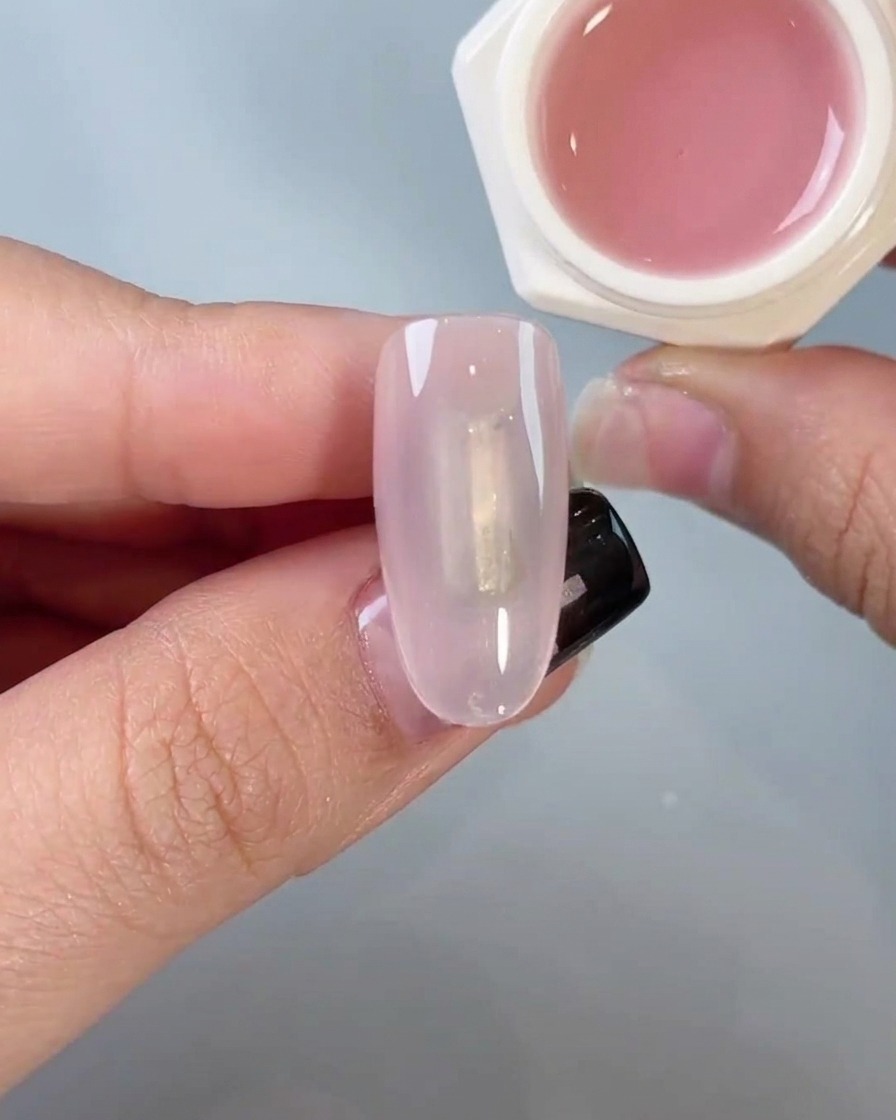 Un applicateur éponge frottant doucement de la poudre chrome sur un ongle pour créer un effet miroir.