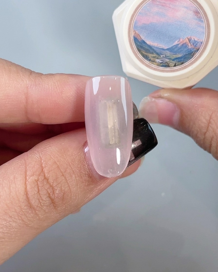 Un pinceau appliquant un top coat transparent sur un ongle chromé à finition miroir.