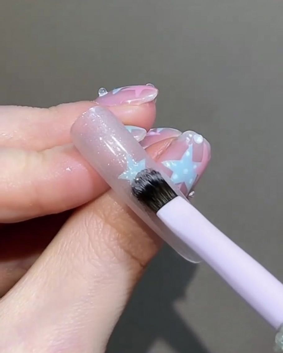 Un petit pinceau plat tapotant et lissant doucement la surface du gel cat-eye humide sur longle.