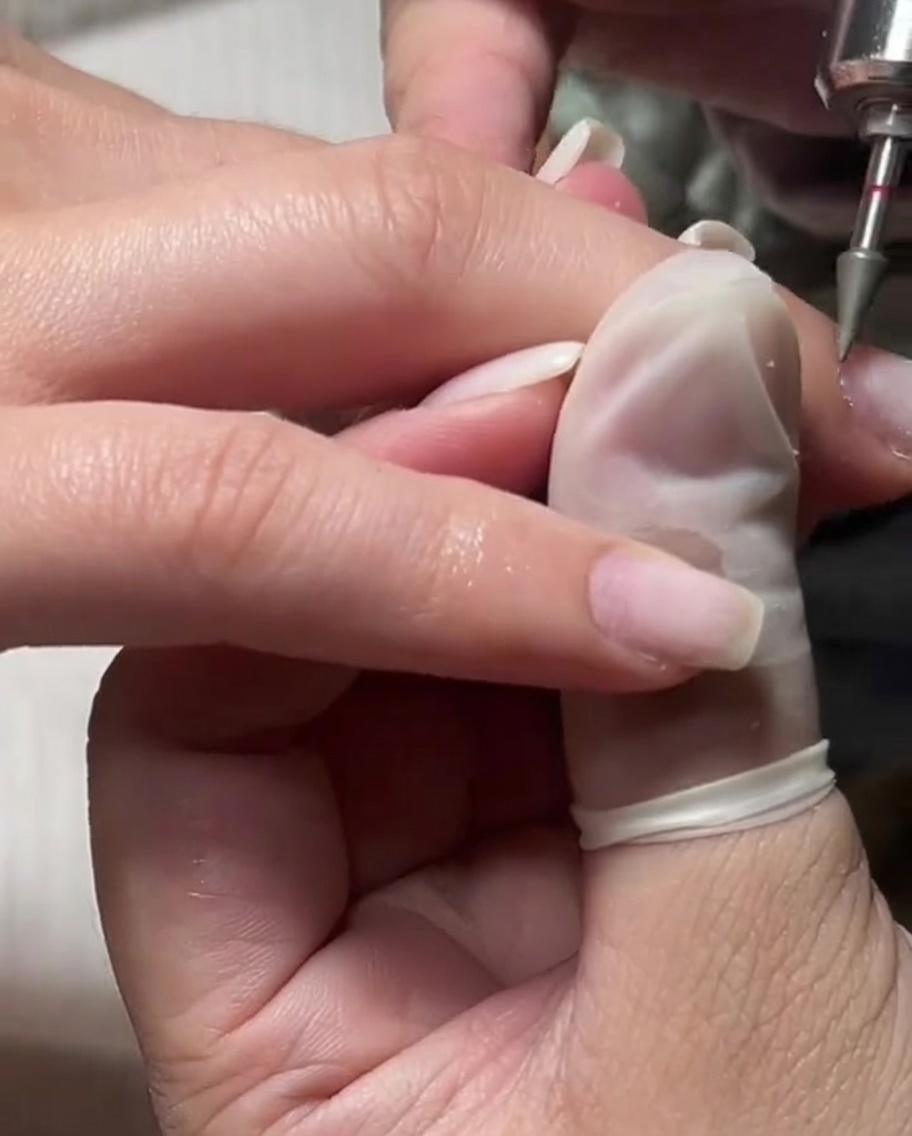 Un embout de ponceuse fin utilisé sur une cuticule humidifiée pour une exfoliation douce.