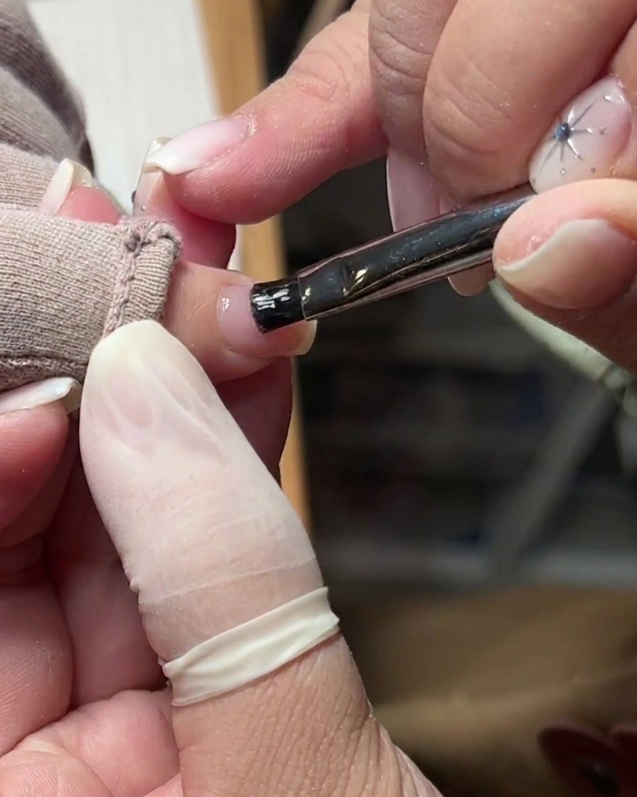 Une brosse douce éliminant la poussière de la surface dun ongle naturel préparé.