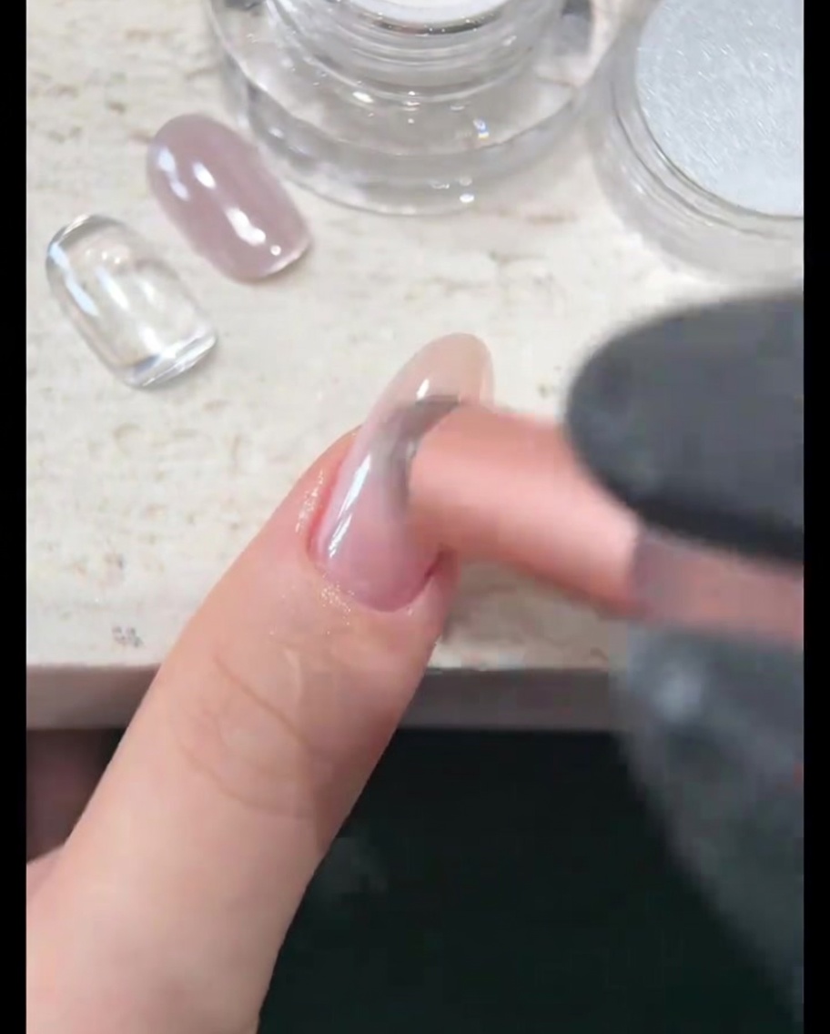 Gros plan sur la surface de longle en cours de polissage jusquà obtenir un éclat miroir nacré brillant.