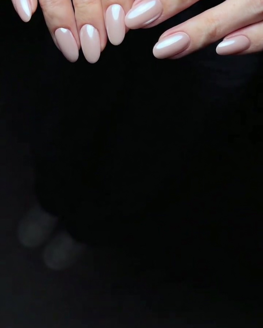 Un pinceau appliquant une deuxième couche de vernis gel rose légèrement plus intense sur un ongle.