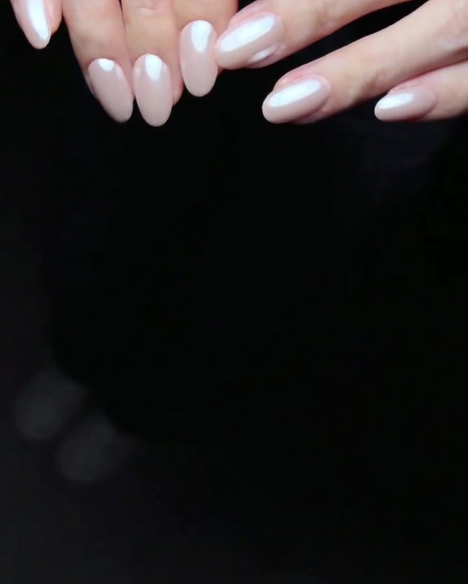 Des ongles avec deux couches de vernis gel rose en train de catalyser à lintérieur dune lampe LED.