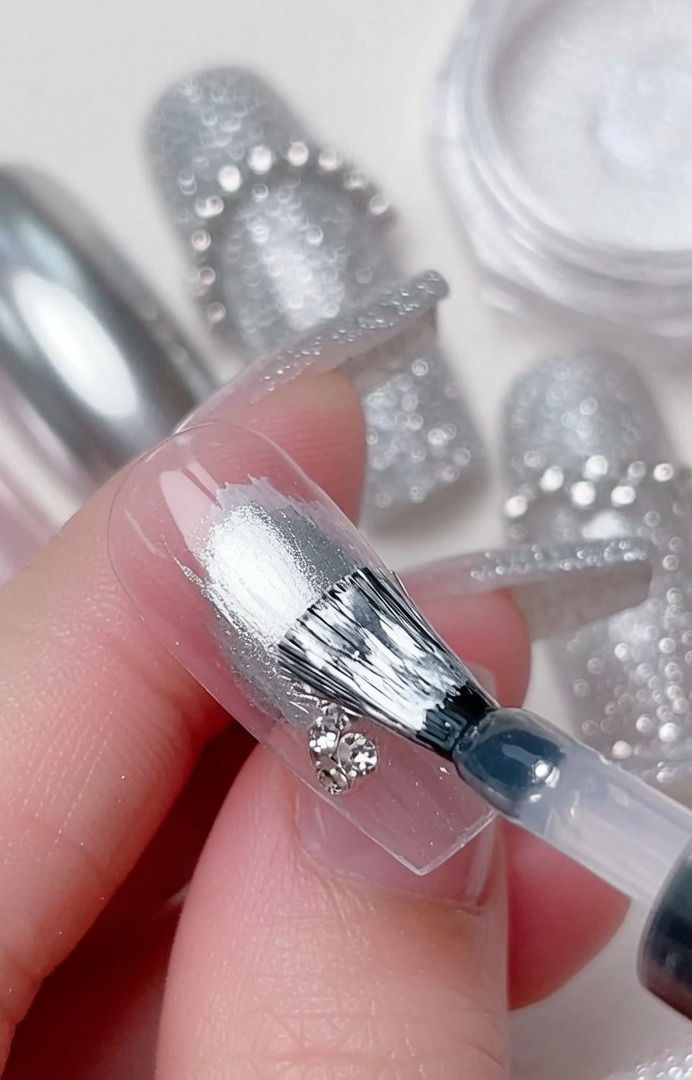 Un pinceau de détail place un strass brillant au centre des courbes en gel.