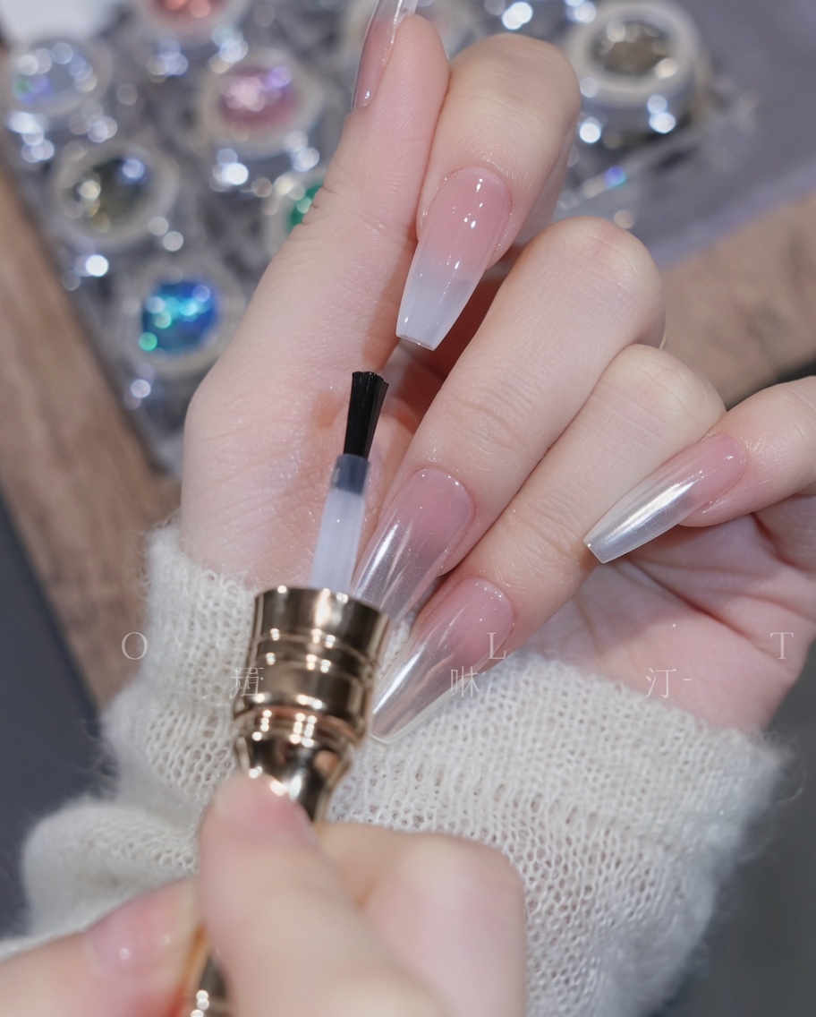 Pinceau appliquant un top coat transparent sur longle dégradé.